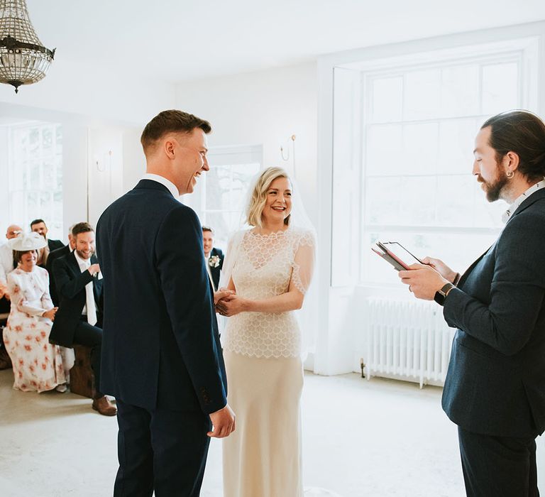 Bride wears Kate Beaumont wedding gown complete with veil over short blonde hair during Humanist wedding ceremony at Aswarby Rectory 