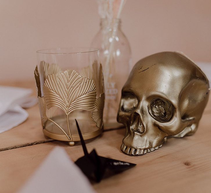 Gold skull wedding decor on wooden table for rustic reception tablescape 