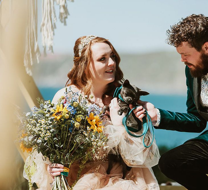 Bride & groom hold their pet dog for wedding day in Cornwall outdoors 