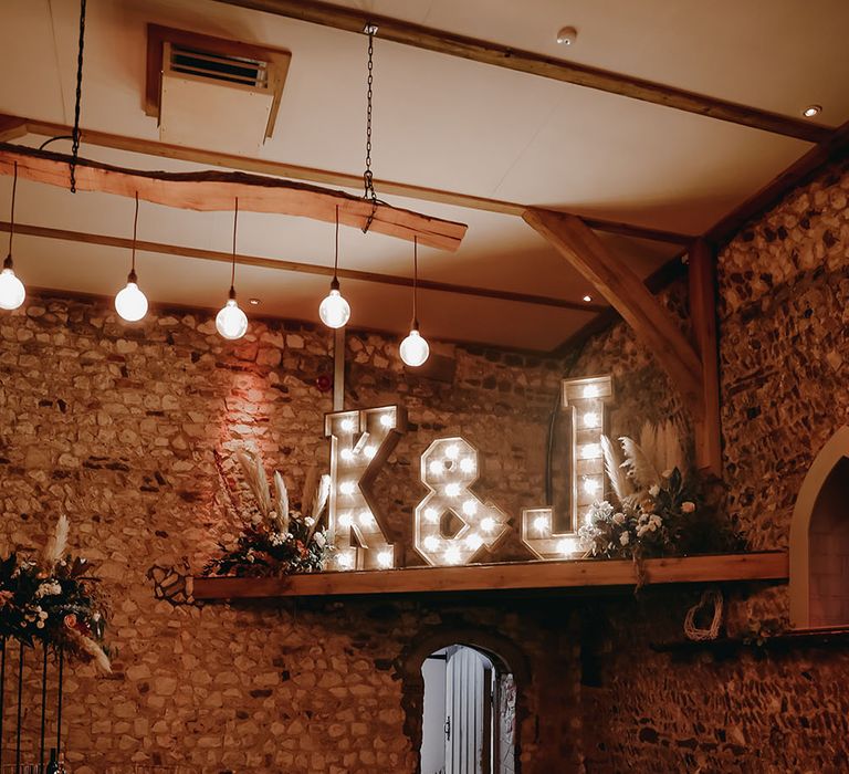 Rustic Pentney Abbey reception room with rounded tables and personalised light up letters against exposed brick