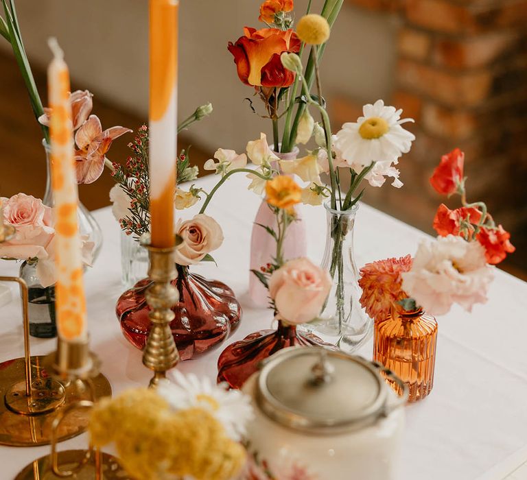 Flower stem decor for the tables with mismatched vases and colourful patterned candles 