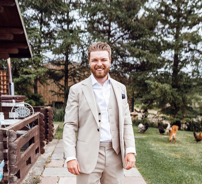 Groom in a cream three piece wedding suit with a dark blue pocket square 