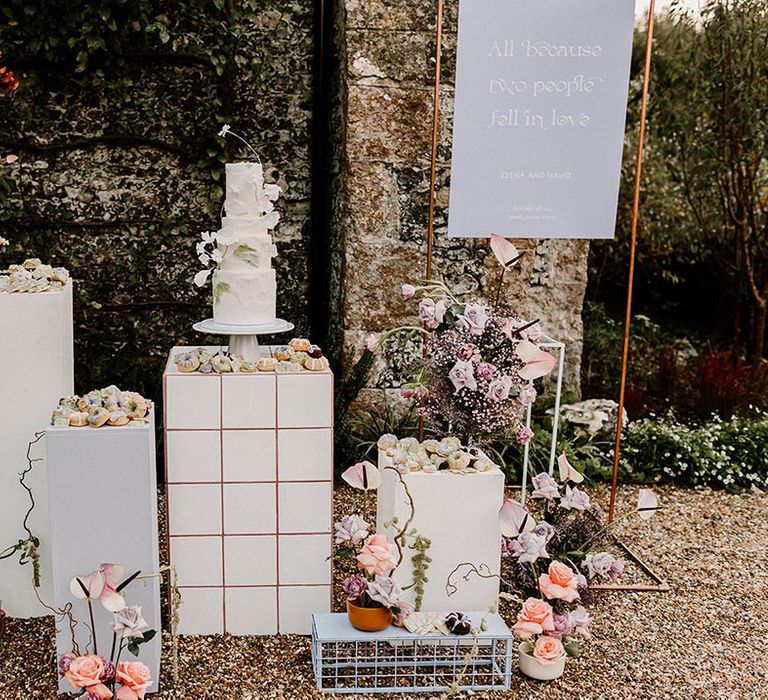 Wedding dessert station with the luxe white iced wedding cake and lavender and white wedding sign