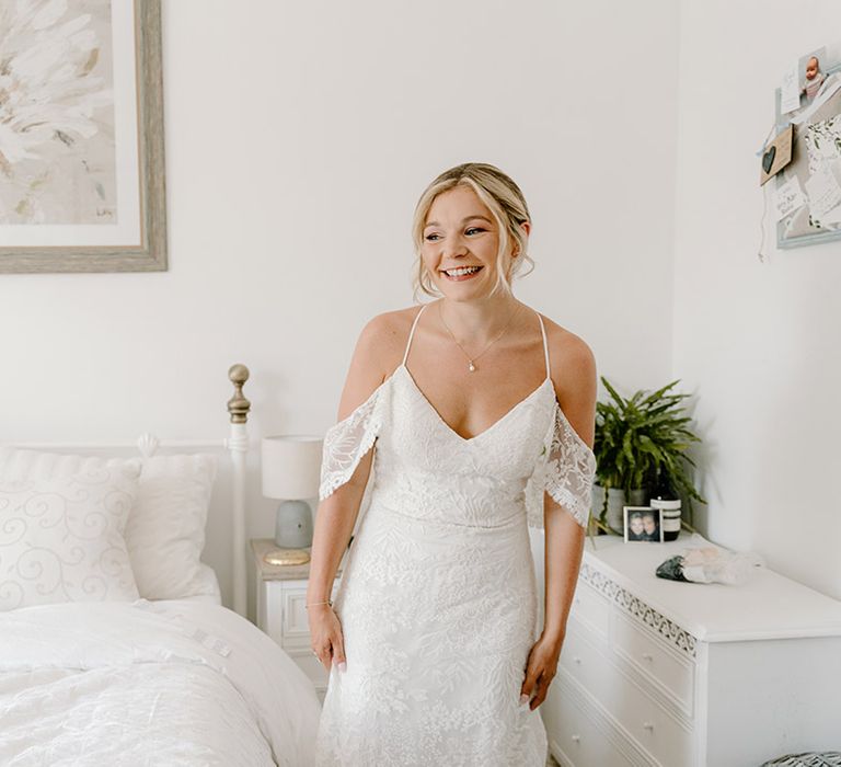 Blonde bride wears lace wedding dress with cold shoulder detailing and fitted style