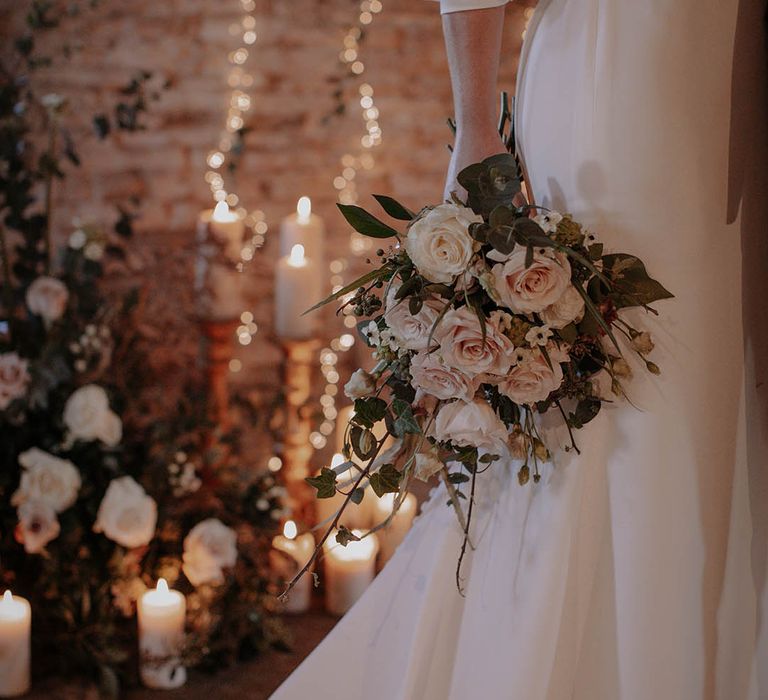 The soft pink rose bridal bouquet with soft candlelights and fairy lights for the altar background decor 