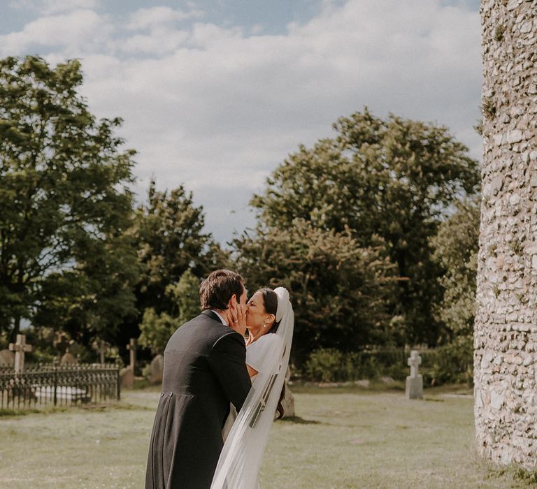 Bride and groom steal a moment together and share a kiss after their church wedding ceremony 