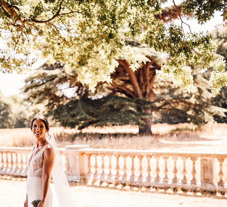 Blue by Enzoani wedding dress with fitted lace and a train carrying white flower and eucalyptus bouquet 