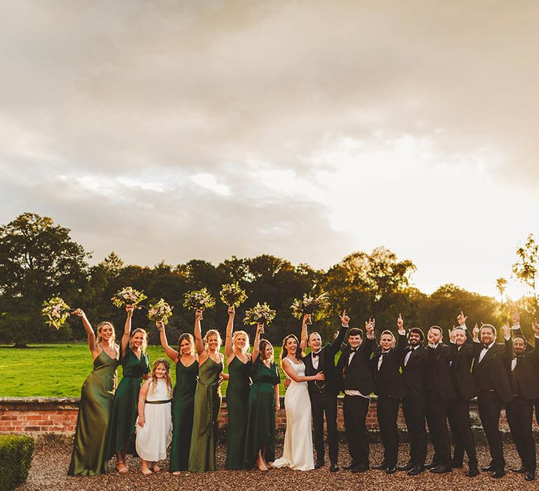 Fun Wedding Photography of I Do Crew wearing black suits and green bridesmaid dresses posing at golden hour