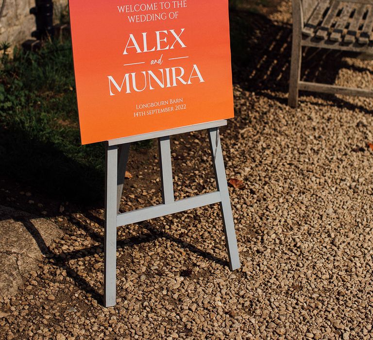 Ombre styled orange and pink wedding signage with white writing 