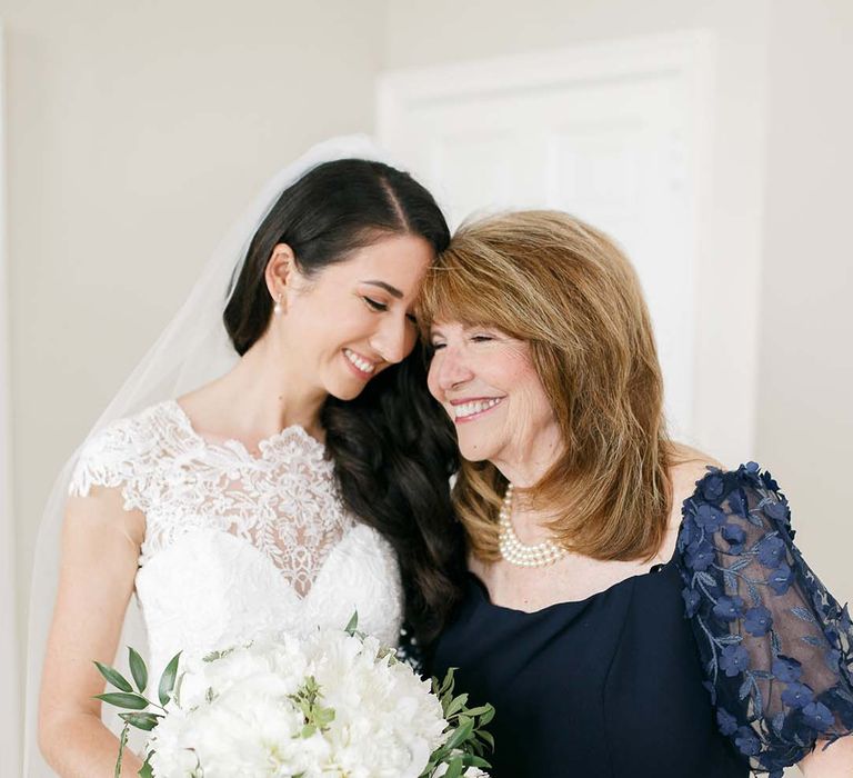 Bride in a Kelly Faetanini wedding dress with her mum in a navy mother-of-the-bride dress with appliqué sleeves