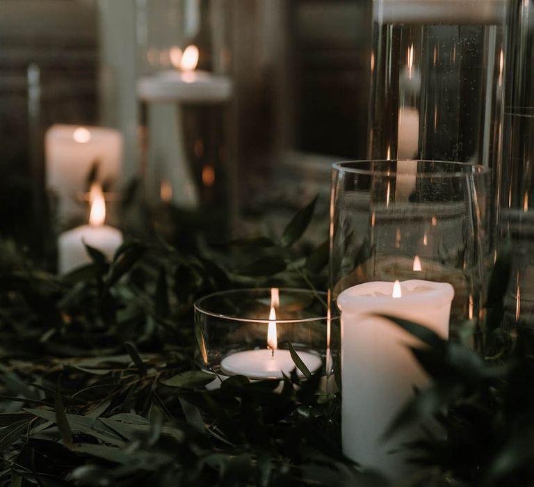 Floating tea lights in glass vases with pillar candles and lots of foliage for cosy and rustic feel 