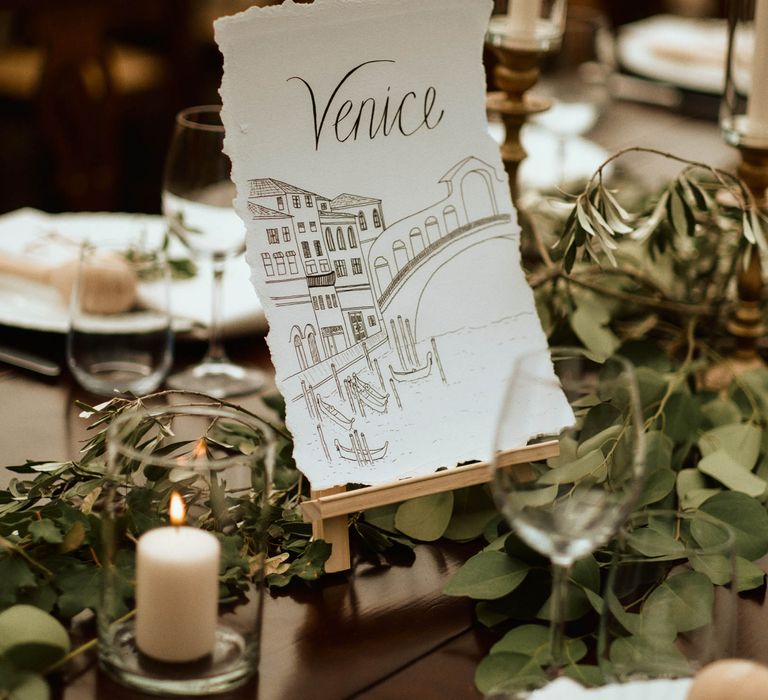 Venice illustrated table name surrounded by ecalyptus on wedding tablescape