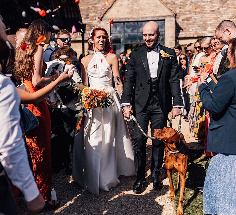 The bride and groom having confetti exit with their pet dog 