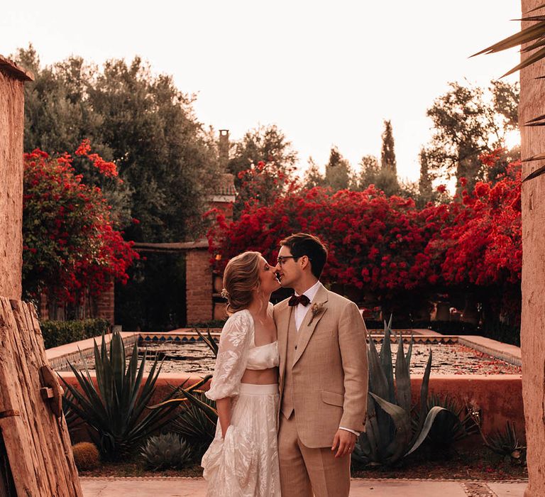 Bride in long sleeve lace crop top and skirt with the groom in three piece cream suit at their Morocco destination wedding 