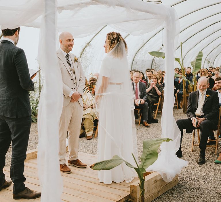 The bride and groom stand facing each other for their Jewish wedding ceremony 