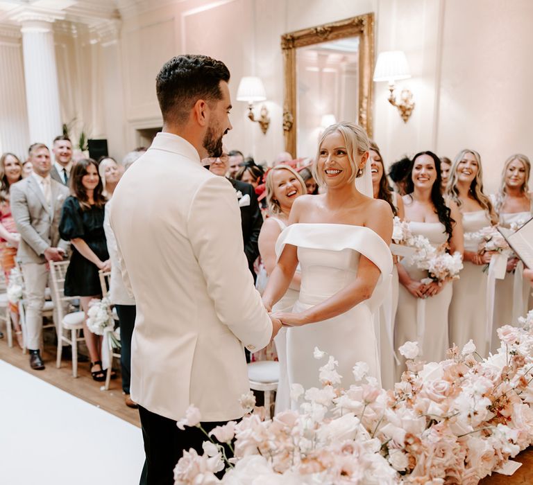 Bride and groom face each other smiling at each other at the altar 