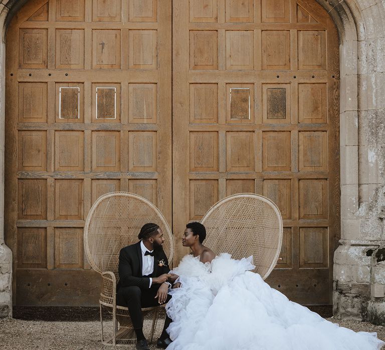 Bride in off the shoulder tulle gown with groom on boho peacock chairs 