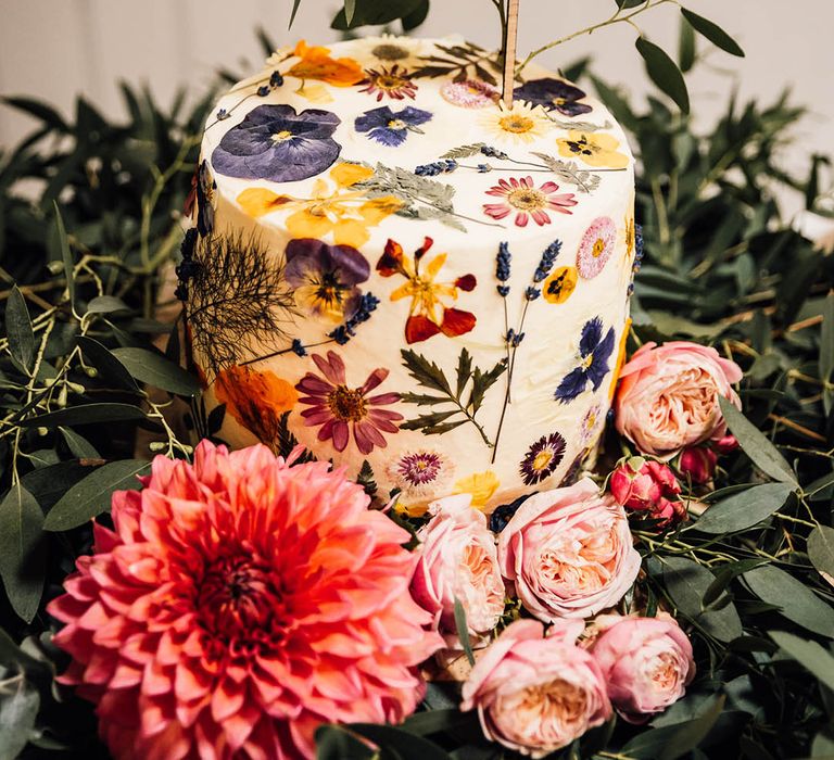 Single tier buttercream iced wedding cake with pressed wildflowers and personalised cake topper 