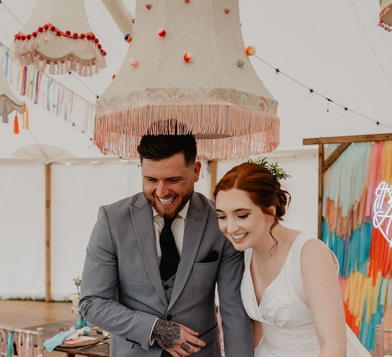 Spotty pom pom lampshade above the bride and groom's head at the boho marquee festival wedding 