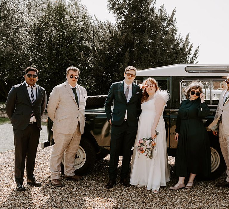 Mixed gender wedding party with groomsmen and best woman posing with the bride and groom 