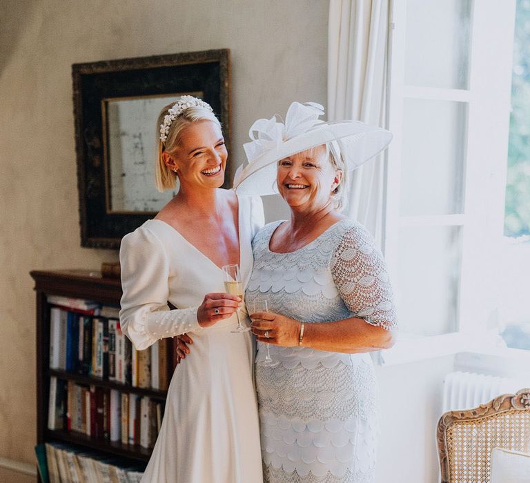 Bride and mother of the bride wearing a blue midi dress sharing a drink on wedding day