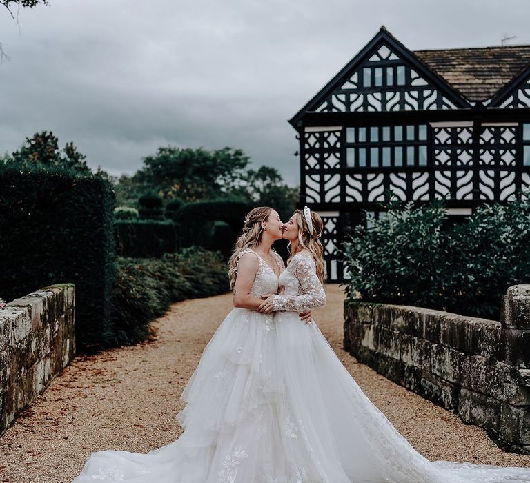 Two brides kissing at their wedding as they pose for couple portraits 