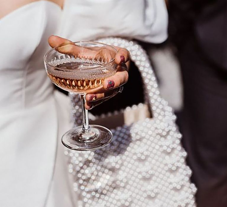 Bride holding a cocktail with her pearl bridal bag handing from her arm by Kitty Wheeler Shaw Photography