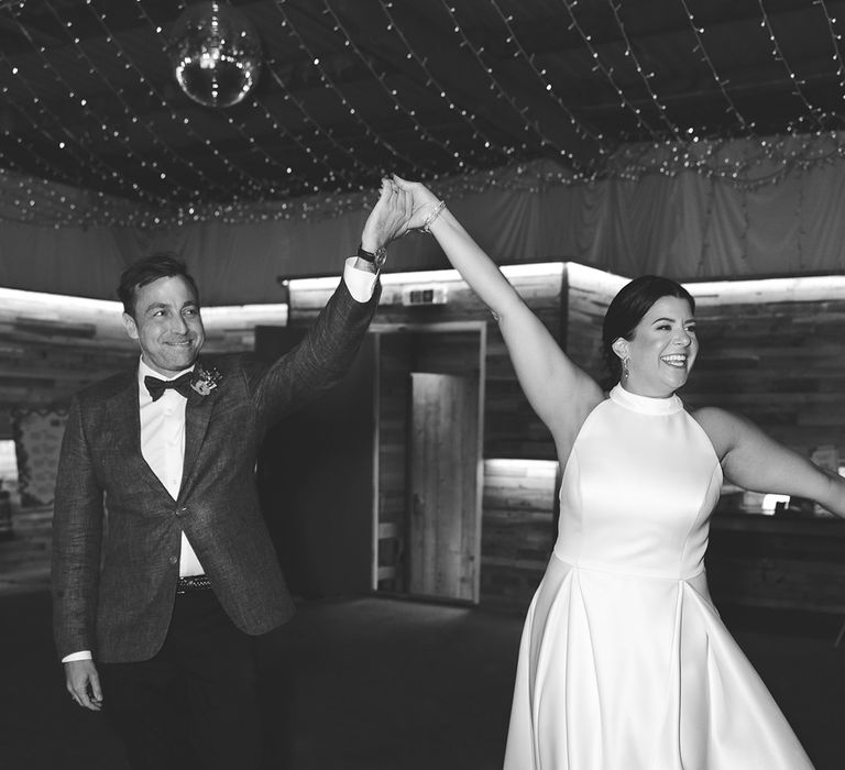 The bride and groom enter their wedding breakfast with their hands in the air