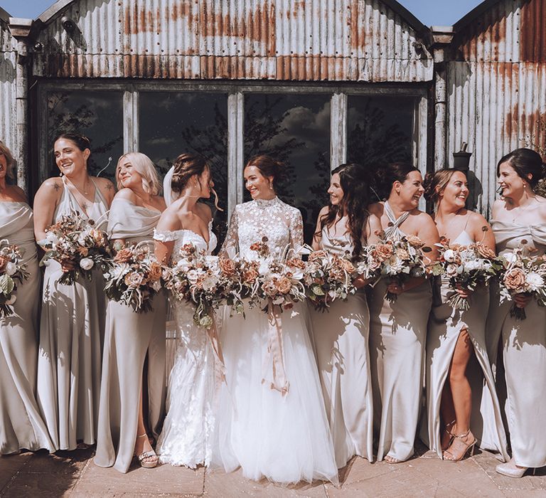 Bridal party wearing green bridesmaid dresses for neutral wedding theme with the two brides 