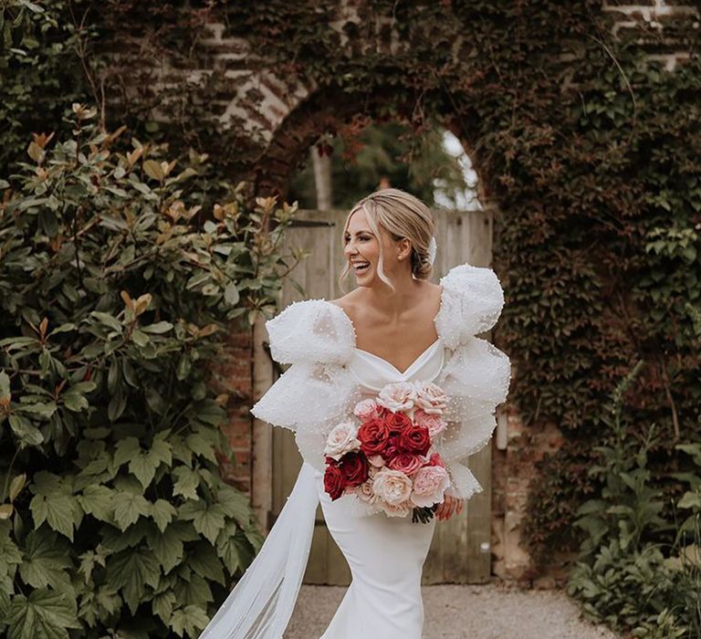 Bride in statement puff sleeve pearl wedding dress with pink and red rose wedding bouquet