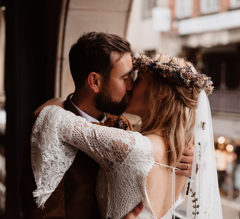 Bride in wedding dress with bell sleeves embracing her husband 