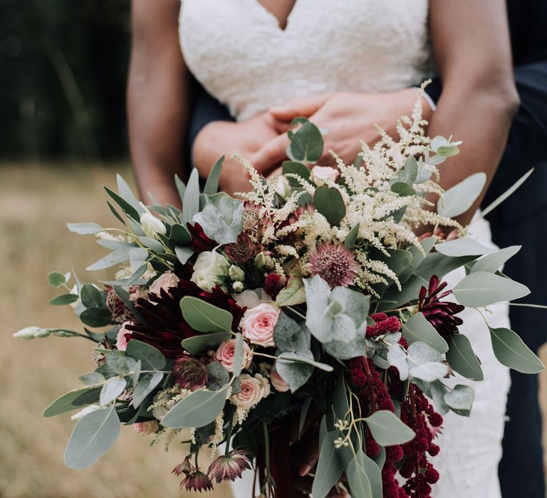 Wedding bouquet with burgundy flowers, eucalyptus, astilbe and spray roses.