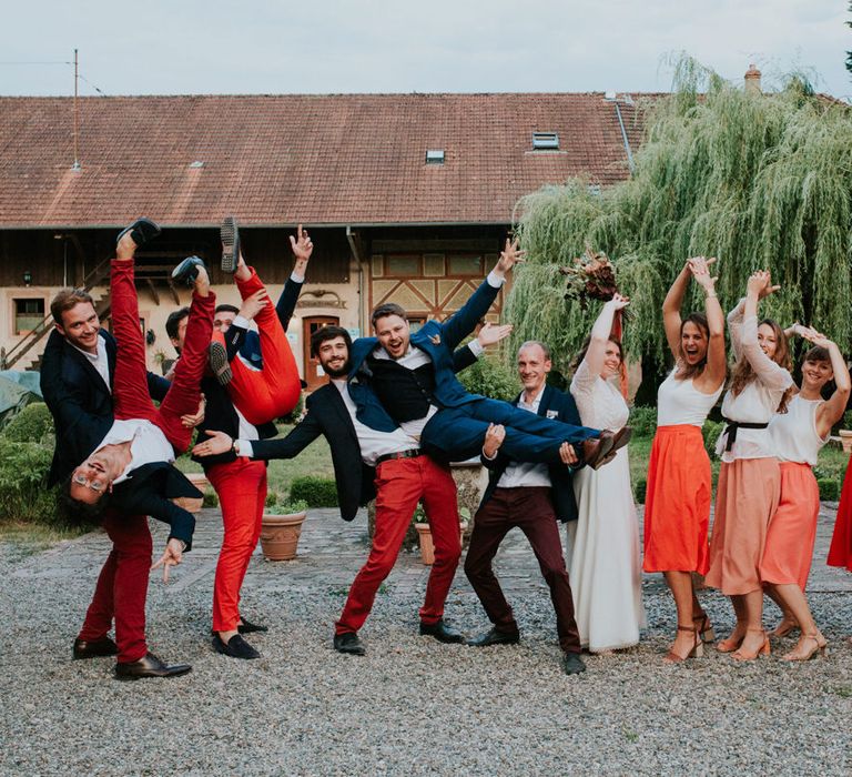 Wedding party portrait with bridesmaids in burnt orange skirts and groomsmen in chinos 