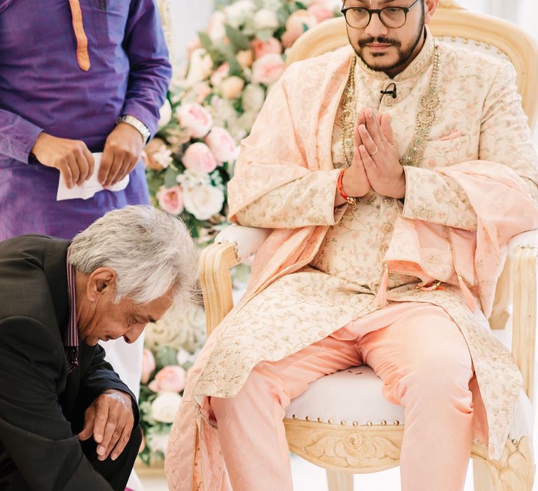 Groom saying a prayer and having his feet cleansed at the Hindu wedding ceremony 