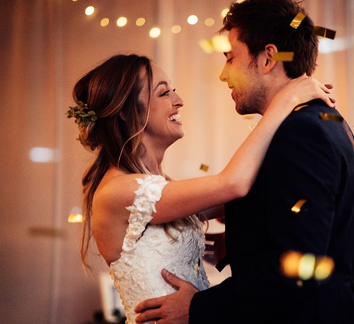 Couple dancing with confetti and cold shoulder wedding dress