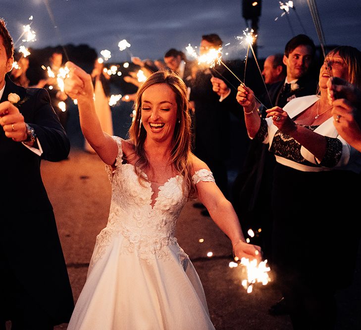 Bride and groom celebrating with sparkles with their wedding guests 