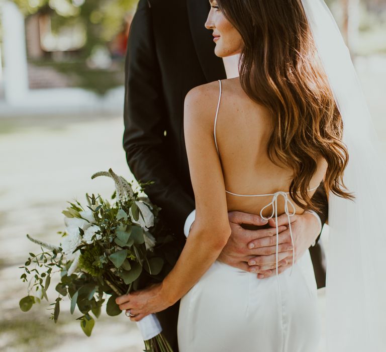 Bride wears an open back wedding dress with elegant thin tie strap