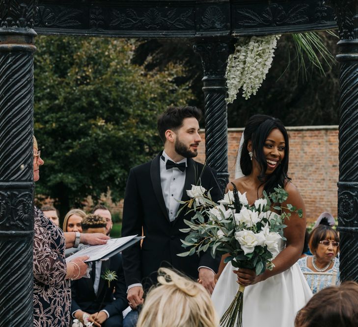 Bride and groom smiling during the outdoor wedding ceremony at Garthmyl Hall in Wales 