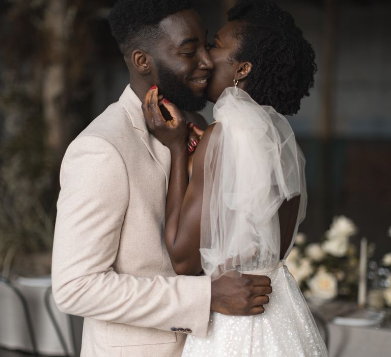 Bride with tulle bow sleeve detail kissing her groom 