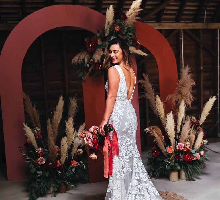 Bride stands in front of floral bouquets with pampas grass