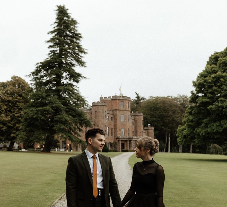 Bride & groom holds hands outdoors 