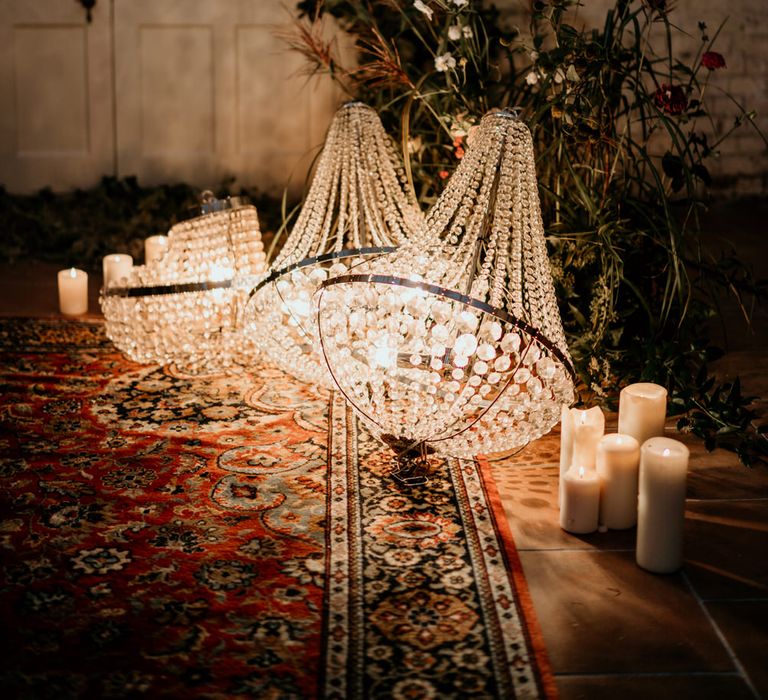 Chandlier's and pillar candles resting on a wool rug to create an intimate ambience in the Our Beautiful Glasshouse wedding venue