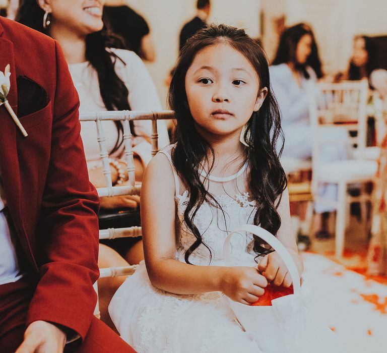 Flower girl sits in chair hold basket