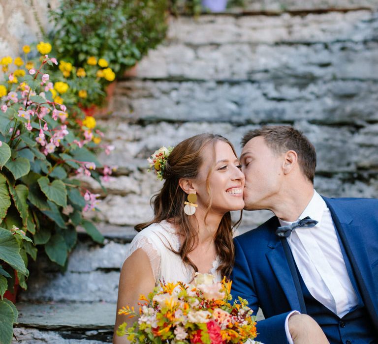 The groom kissing the bride on the cheek at their destination wedding in Greece