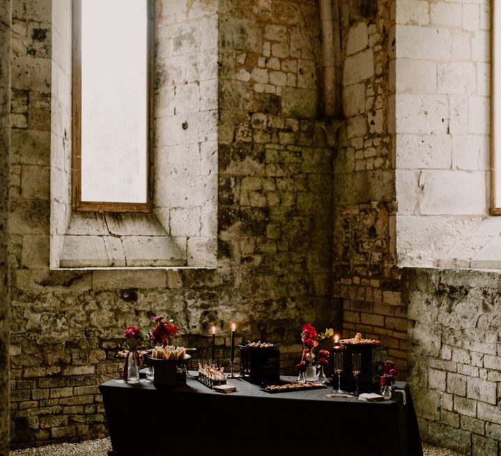 Dessert table with black tablecloth, candles and red wedding flowers 