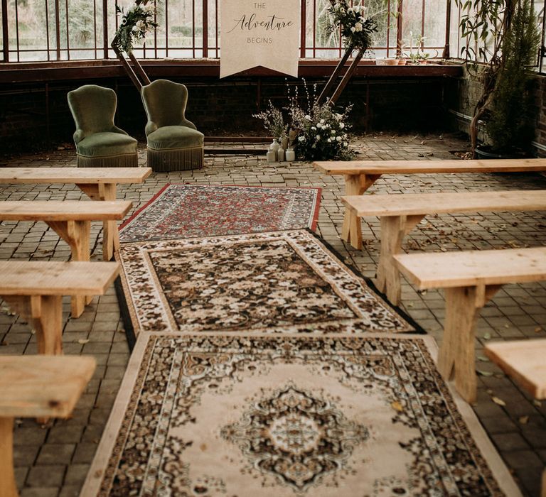 Glasshouse wedding ceremony with wool rugs, wooden geometrical altar, fabric sign and greenery decor 