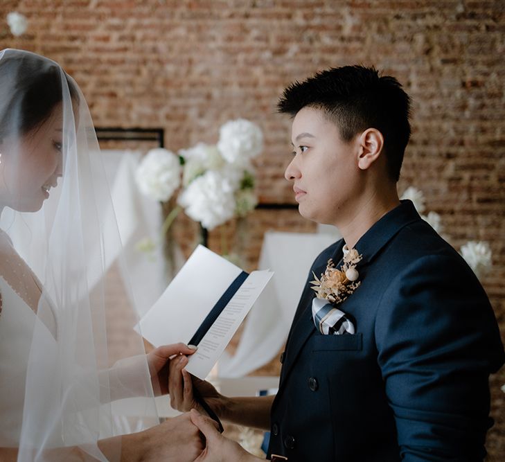 Brides reading their vows at their intimate Asian Lesbian wedding ceremony 