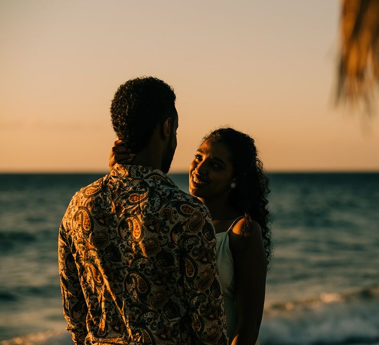 Bride & groom stand in front of sea in Greece 