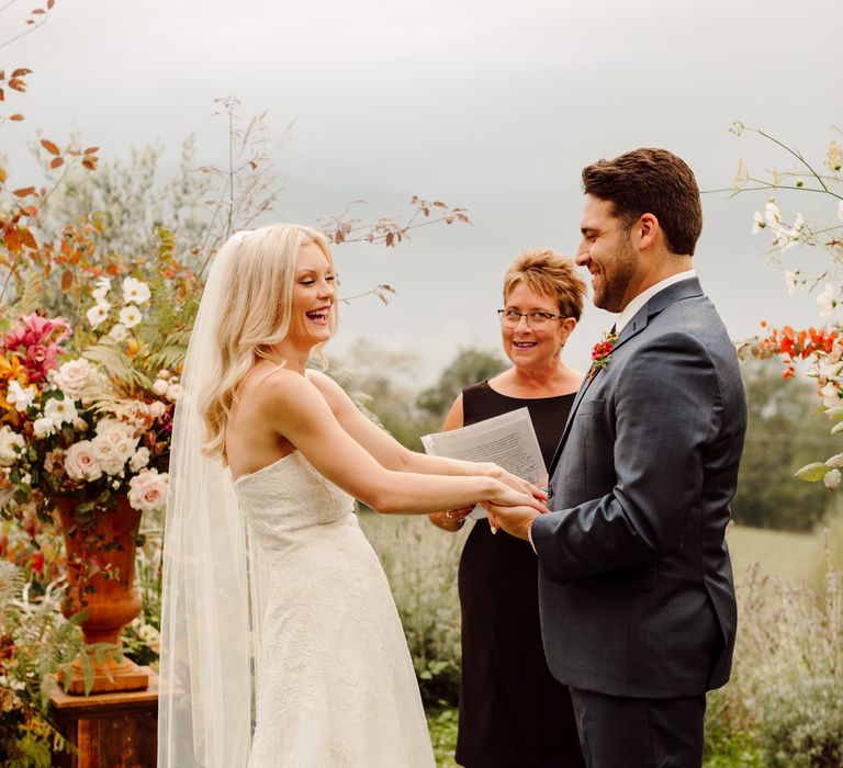 The bride and groom laughing at the altar hand in hand as they get married