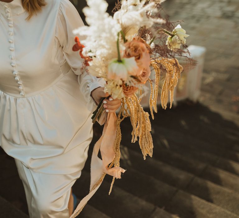 Bride walks with floral bouquet with dried flowers and pampas grass